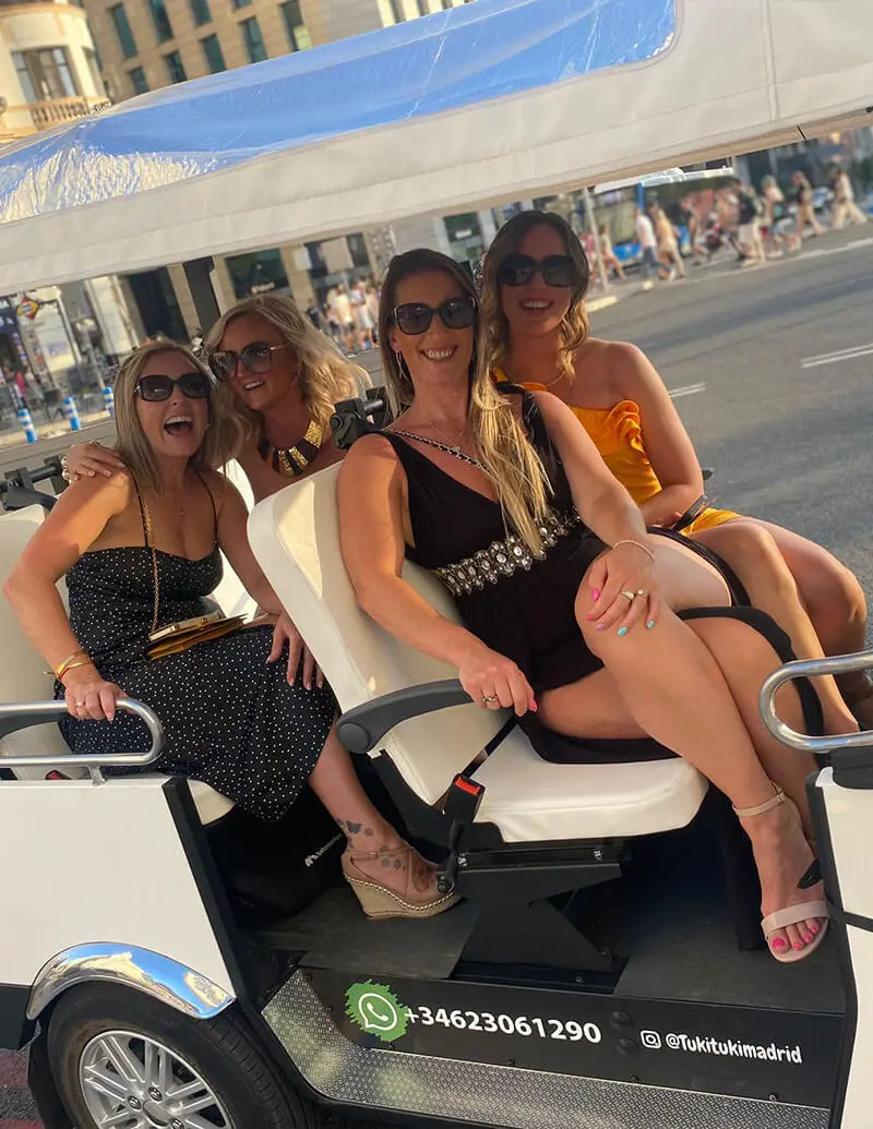 Grupo de amigas riendo y disfrutando de un paseo en tuk tuk por Madrid.